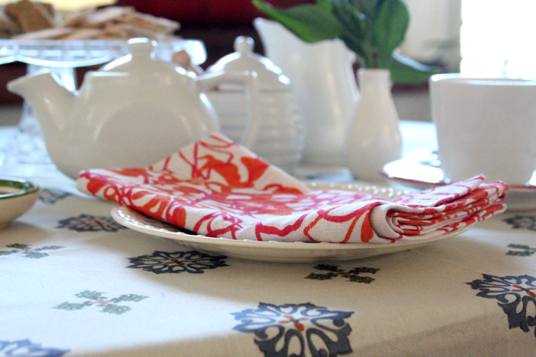 foldeded pink and white napkin on a table set for tea.